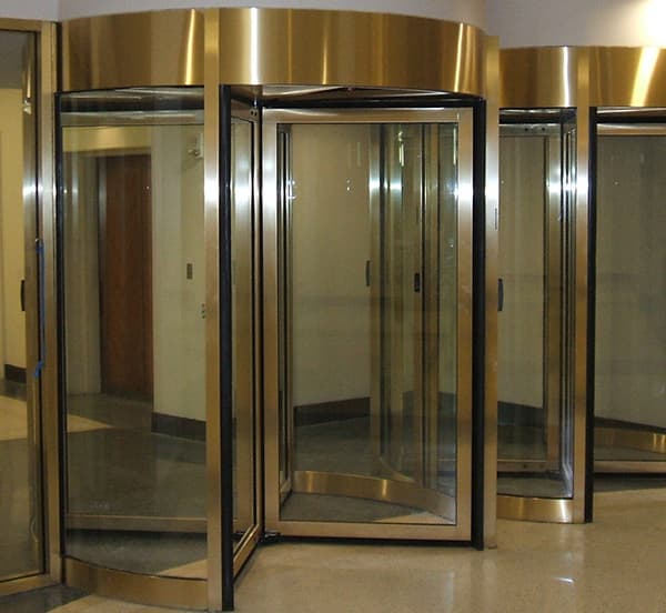 Bank of brass-framed commercial revolving doors in a building lobby