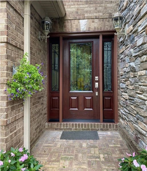 Stained wood entry door with decorative iron-and-glass sidelights